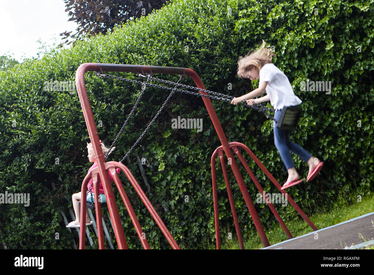 Zwei Latina Mädchen, auf Schaukeln in einem Park auf einem Spielplatz Stockfoto