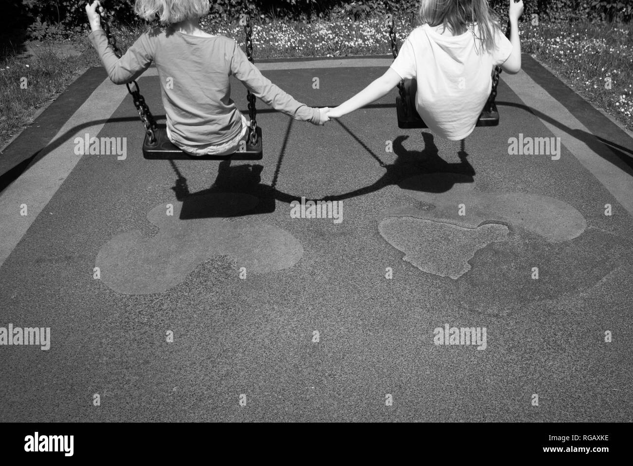 B; acl und weiß Foto von zwei Latina Mädchen, auf Schaukeln in einem Park auf einem Spielplatz Stockfoto