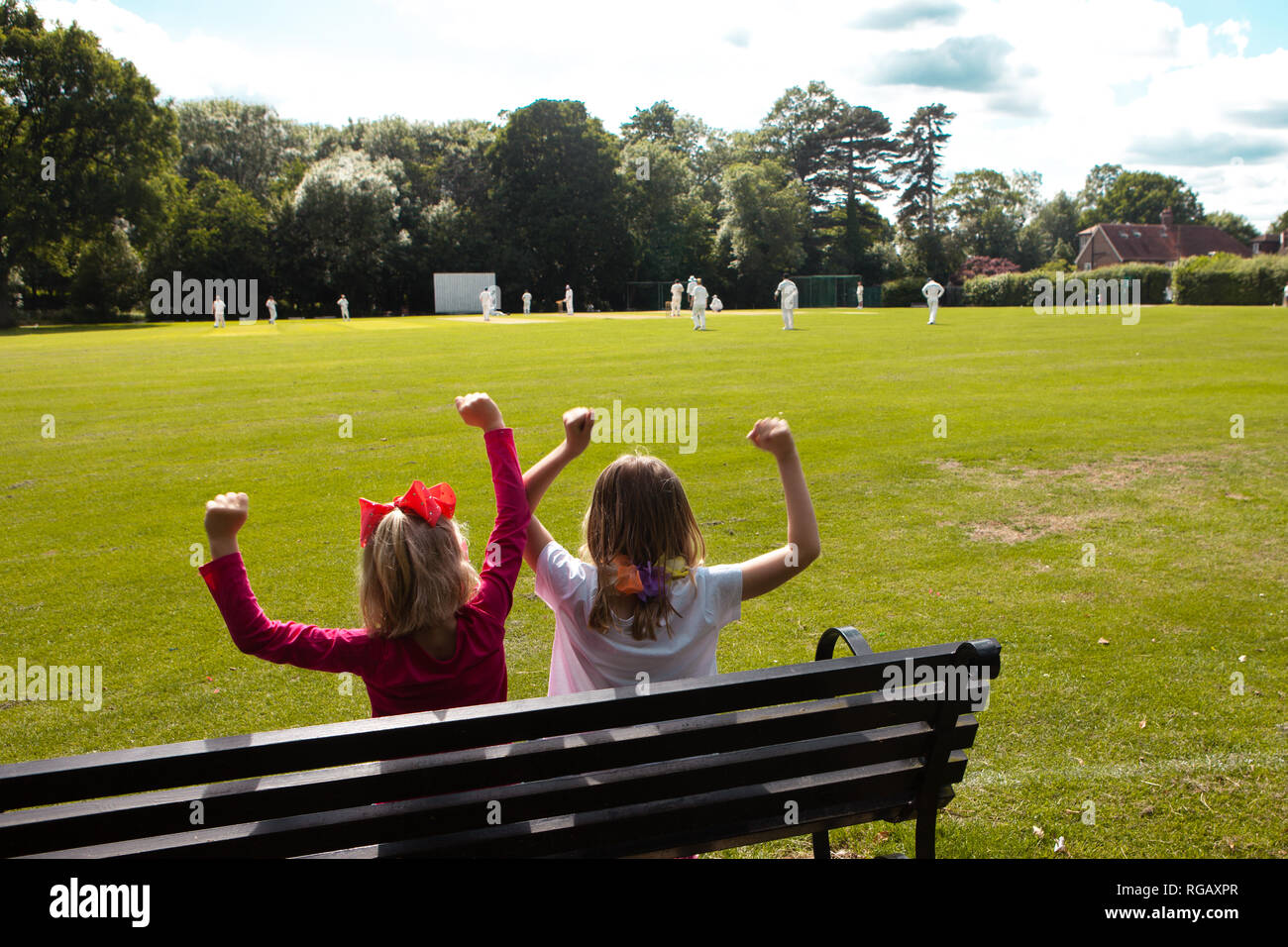 Zwei junge Mädchen auf einer Parkbank Cricket beobachten Stockfoto