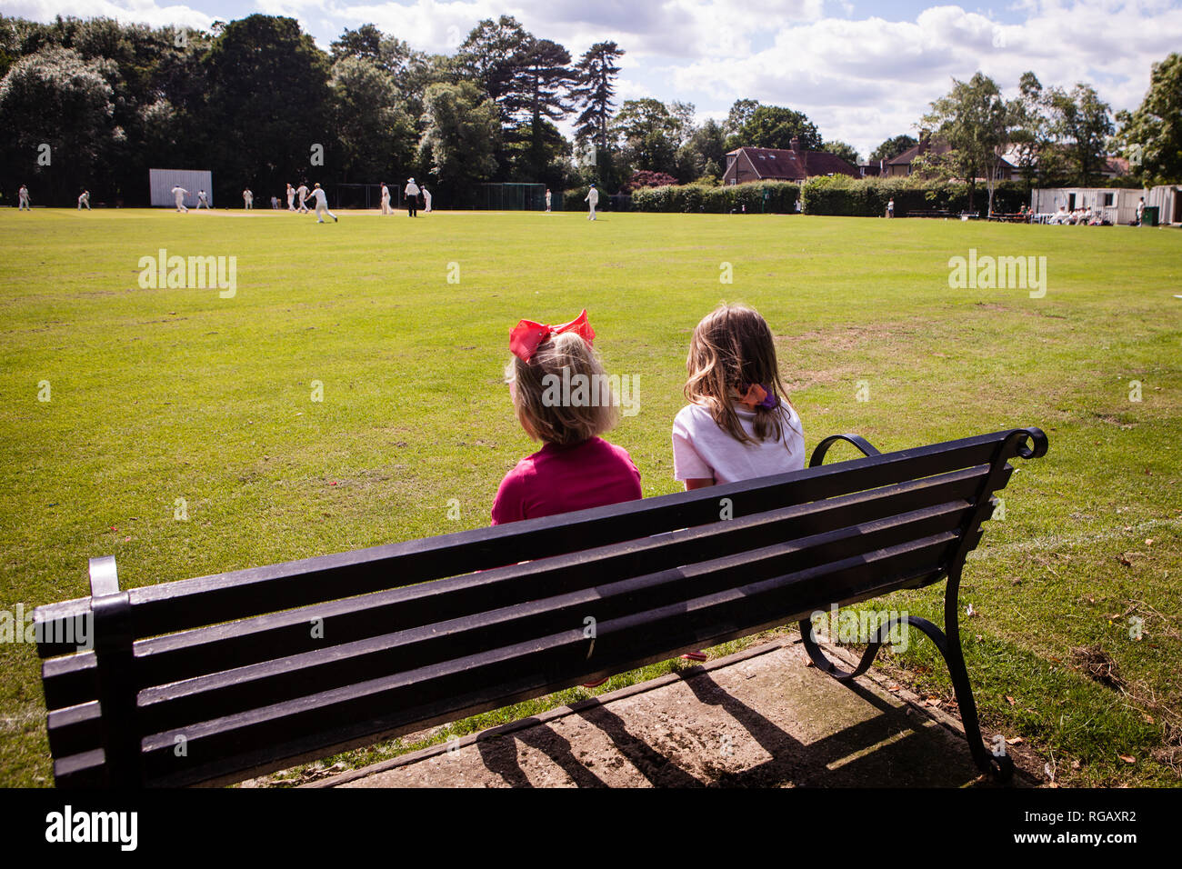 Zwei junge Mädchen auf einer Parkbank Cricket beobachten Stockfoto