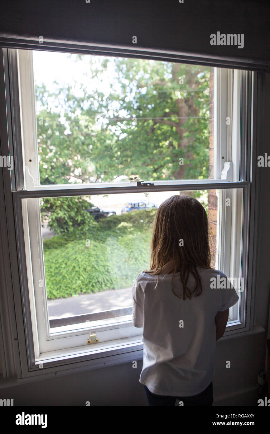 Die Rückseite eines jungen Mädchens durch ein Fenster Stockfoto