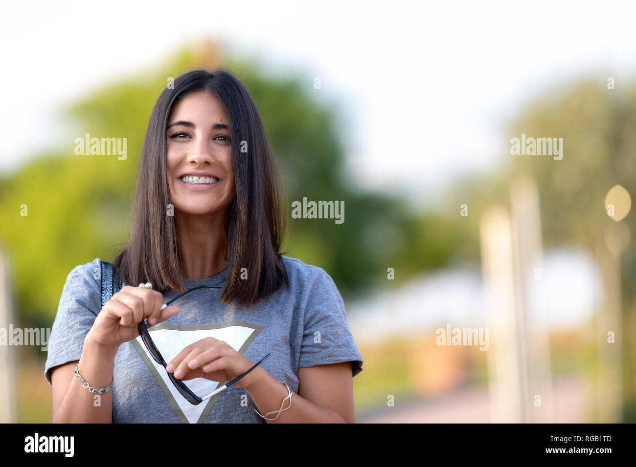 Schönheit ihre Sonnenbrille Holding in einer unscharfen Park. Stockfoto