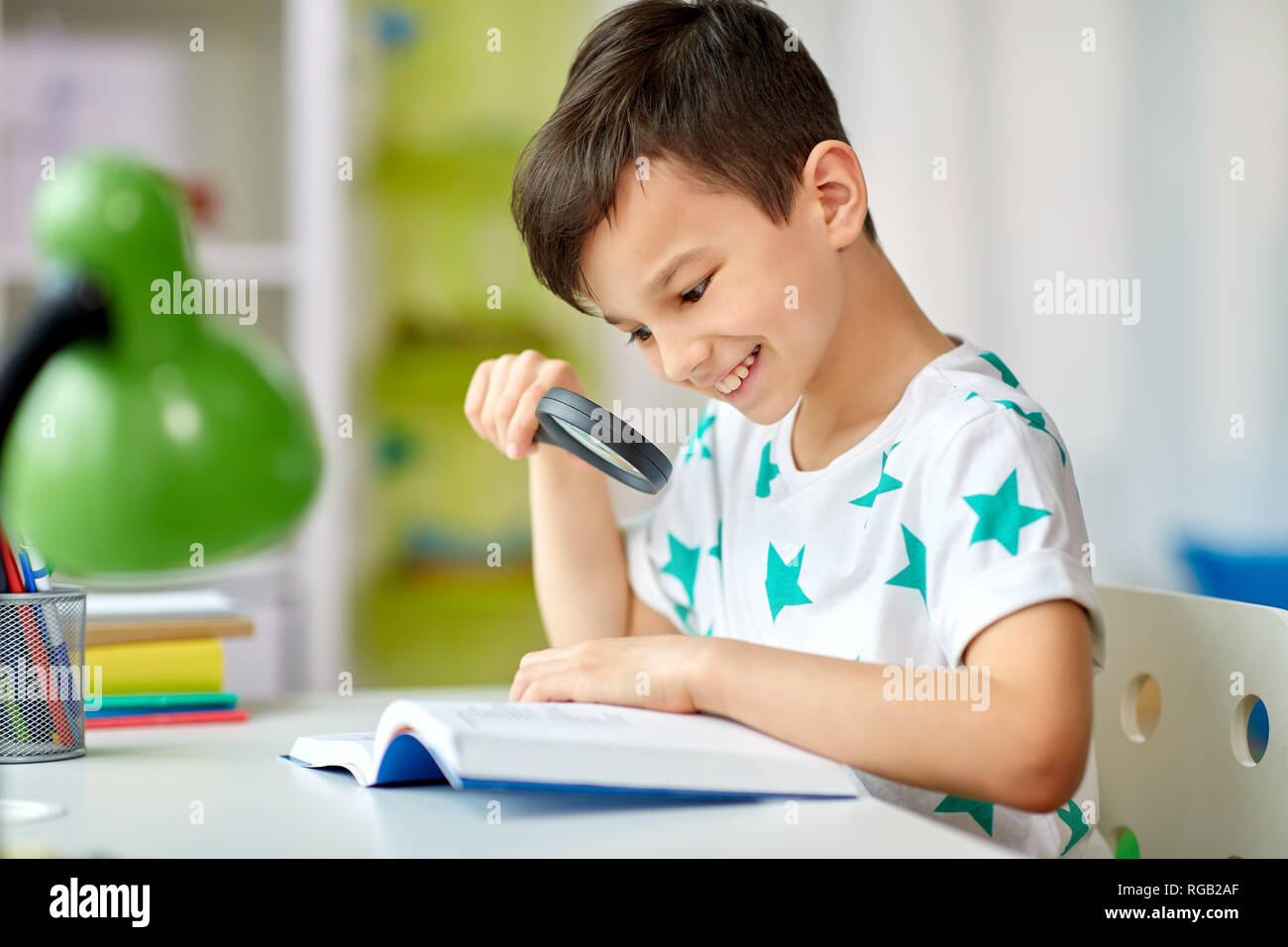 Junge mit Lupe lesen Buch zu Hause Stockfoto