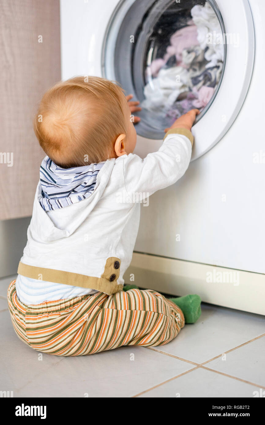 Baby Boy in den Zyklen der Waschmaschine Wäsche interessiert Stockfoto