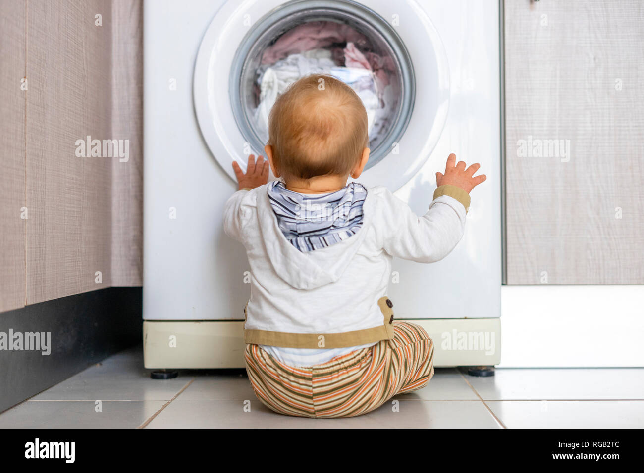 Baby Boy in den Zyklen der Waschmaschine Wäsche interessiert Stockfoto