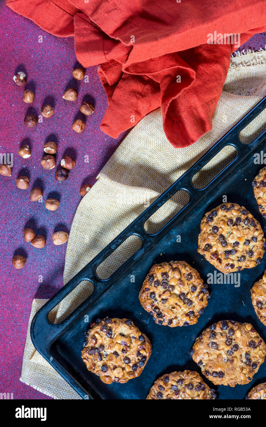 Avena cookies mit Haselnüssen und Chocolate Chips auf ein Backblech und einige Haselnüsse und Tücher Stockfoto