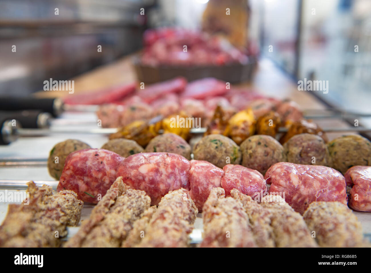 Detail der frischen, rohen Würste Spieß und andere Variationen von zubereiteten Fleisch in Metzgerei Zähler konzentrieren sich auf den Vordergrund Stockfoto
