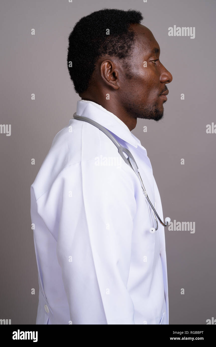 Junge schöne afrikanischer Mann Arzt gegen grauer Hintergrund Stockfoto