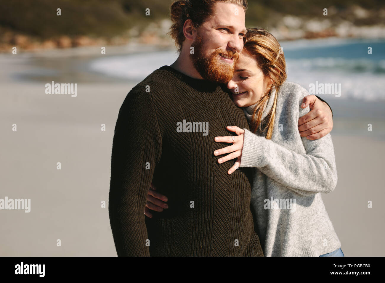 Liebespaar stehend draußen am Strand. Kaukasische Frau in ihrer Freunde Arme und lächelnd an der Küste. Stockfoto