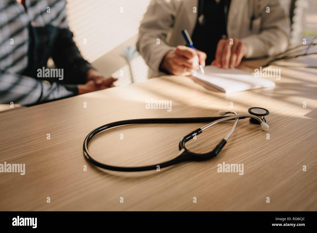 Stethoskop auf Tabelle mit weiblichen Arzt Arzneimittel verschreiben, um ihre Patienten. Arzt schreiben Medizin Rezept für die männlichen Patienten. Stockfoto