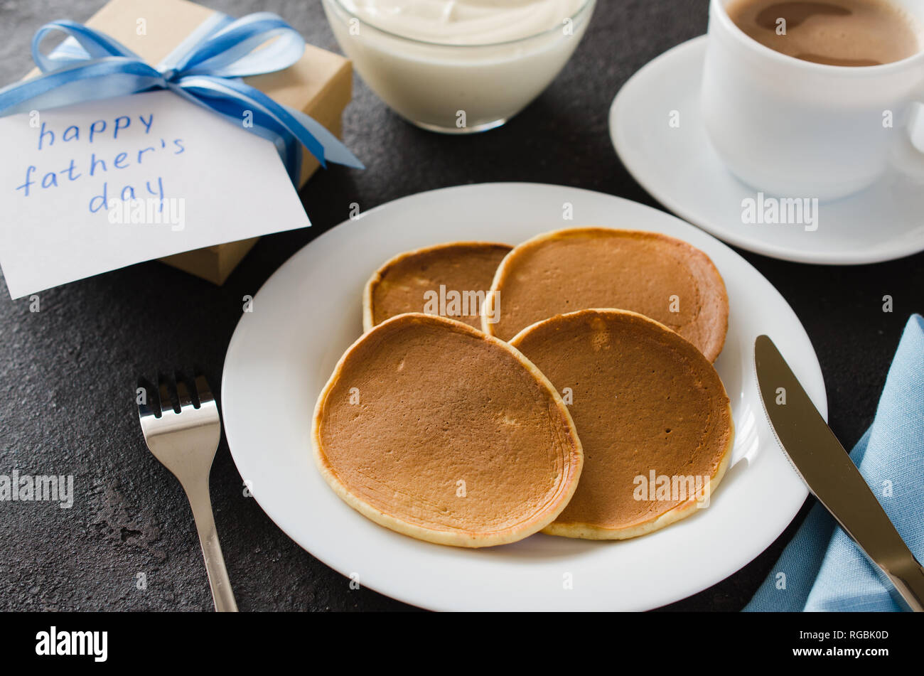 Frühstück für Vater. Hausgemachte klassische amerikanische Pfannkuchen und eine Tasse Kaffee mit Milch. Vatertag Konzept. Stockfoto