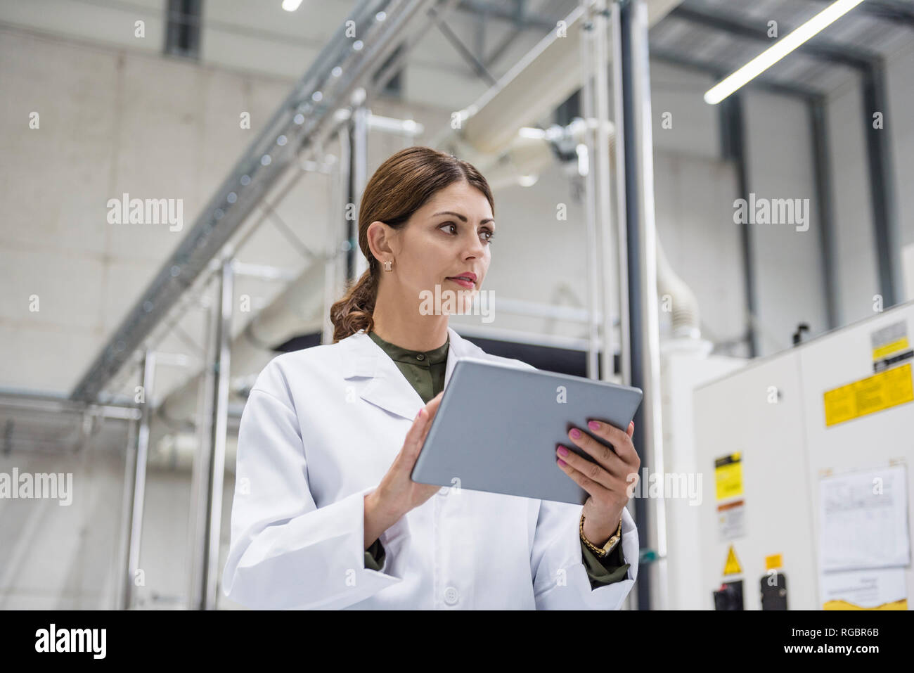 Frau Kontrolle der Fertigung Maschinen in High Tech Unternehmen, indem Sie digitale Tablet Stockfoto