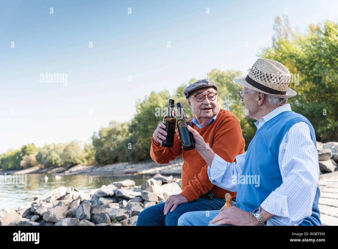 Alte Freunde sitzen am Flussufer, Bier trinken. Stockfoto