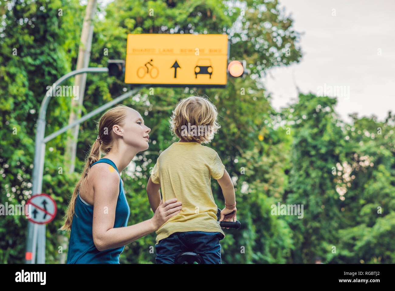 Mom zeigt seinem Sohn eine Platte der Gemeinschafts-Lane und Vorsicht Fahrrad Warnschild Stockfoto