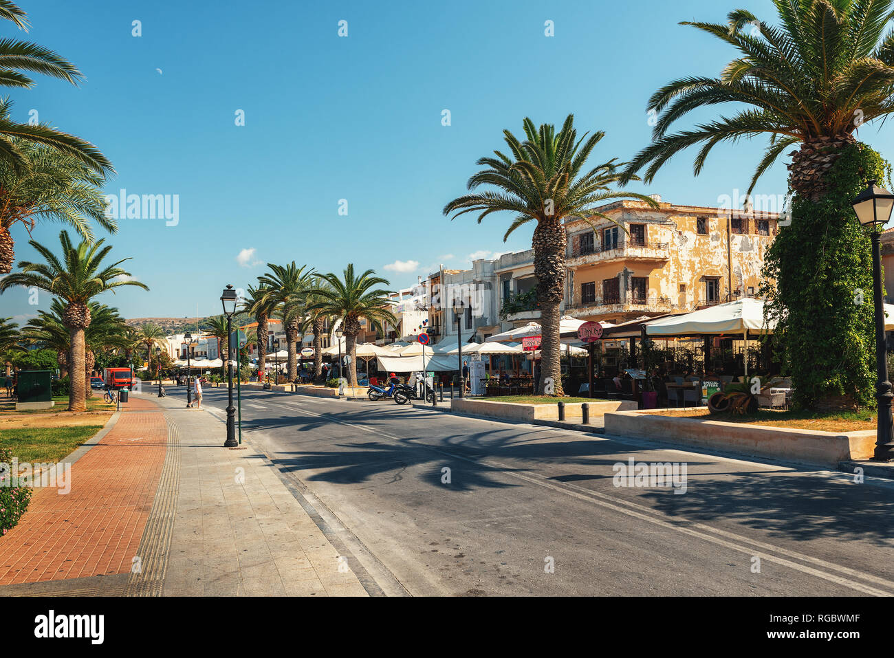 RETHYMNO, Griechenland - AUGUST 2018: Zentrale Straße der Stadt mit Promenade und Palmen entlang es Stockfoto