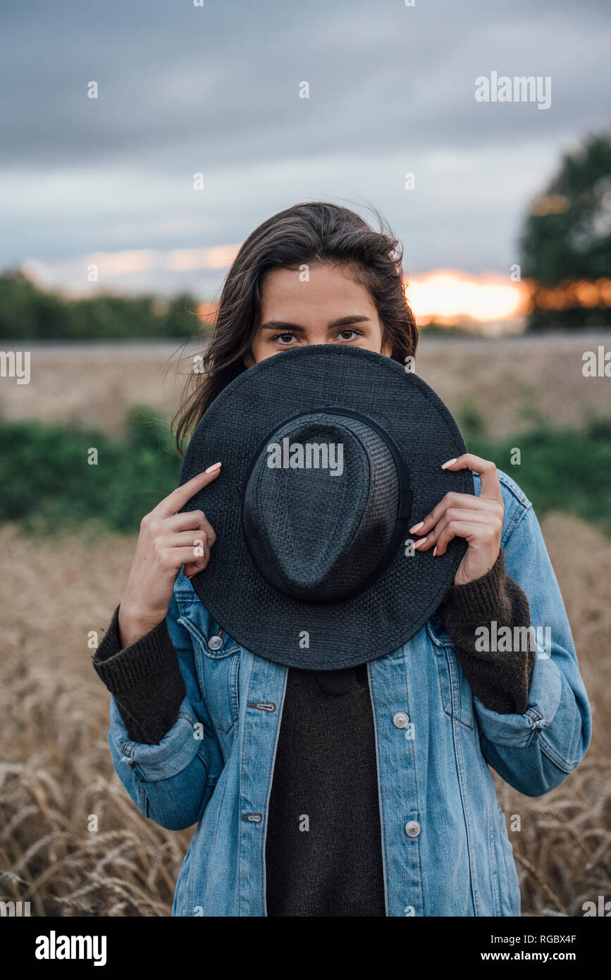 Porträt der jungen Frau versteckt sich hinter schwarzen Hut Stockfoto
