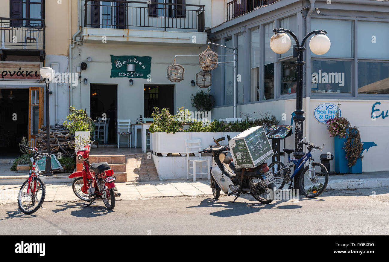 RETHYMNO, Griechenland - AUGUST 2018: Fahrräder und Mopeds sind einem Aufenthalt in der Nähe von traditionellen griechischen Taverne auf Kreta geparkt Stockfoto