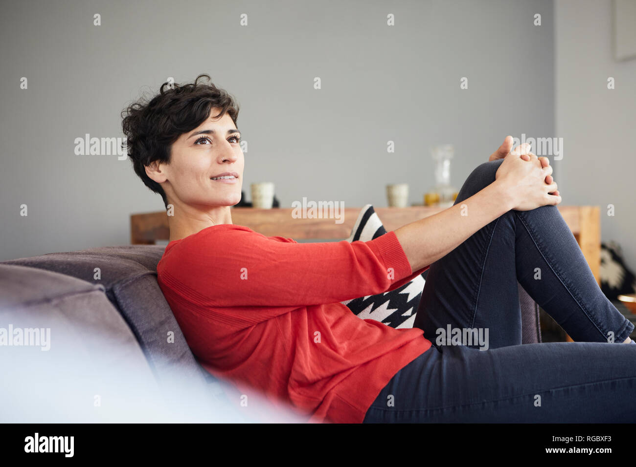 Porträt der lächelnde Frau auf der Couch zu Hause denken Stockfoto