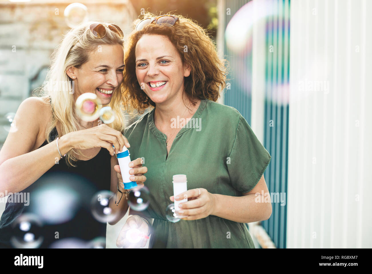 Zwei glückliche Frauen mit Seifenblasen im Freien Stockfoto