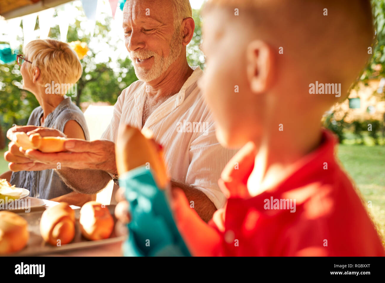 Ältere Menschen Vorbereiten einer heißen Hund auf einer Gartenparty Stockfoto