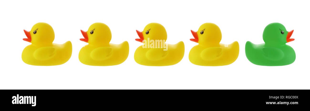 Gelbe Enten in einer Reihe mit Green Duck gehen falsche Weise auf Weiß mit Freistellungspfad isoliert Stockfoto