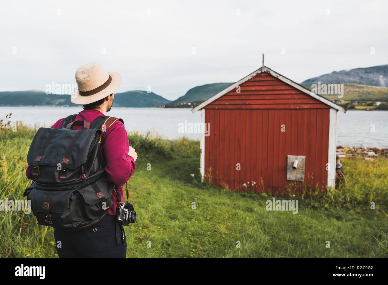 Junger Mann mit Rucksack erkunden Red Barn in Nordnorwegen Stockfoto