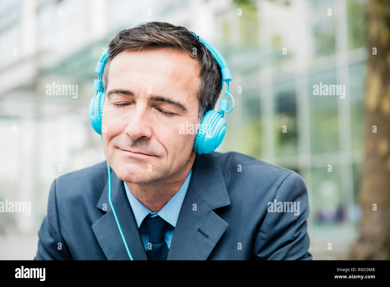 Geschäftsmann mit geschlossenen Augen Hören von Musik über Kopfhörer in der Stadt Stockfoto