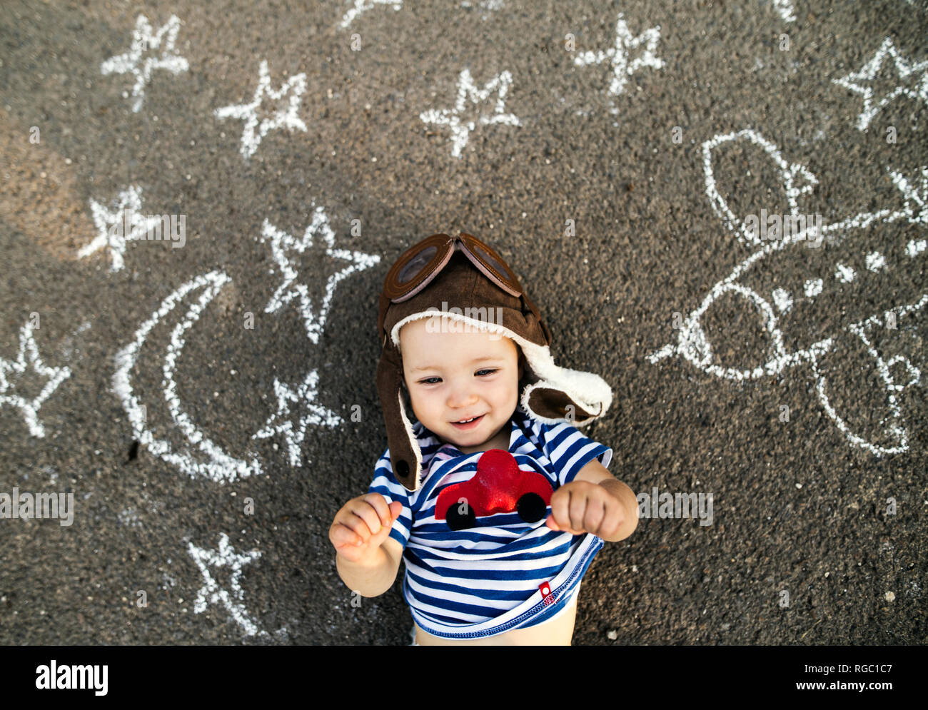 Portrait von lächelnden Mädchen tragen Pilot hat auf Asphalt mit Flugzeug, Mond und Sternen bemalt Stockfoto