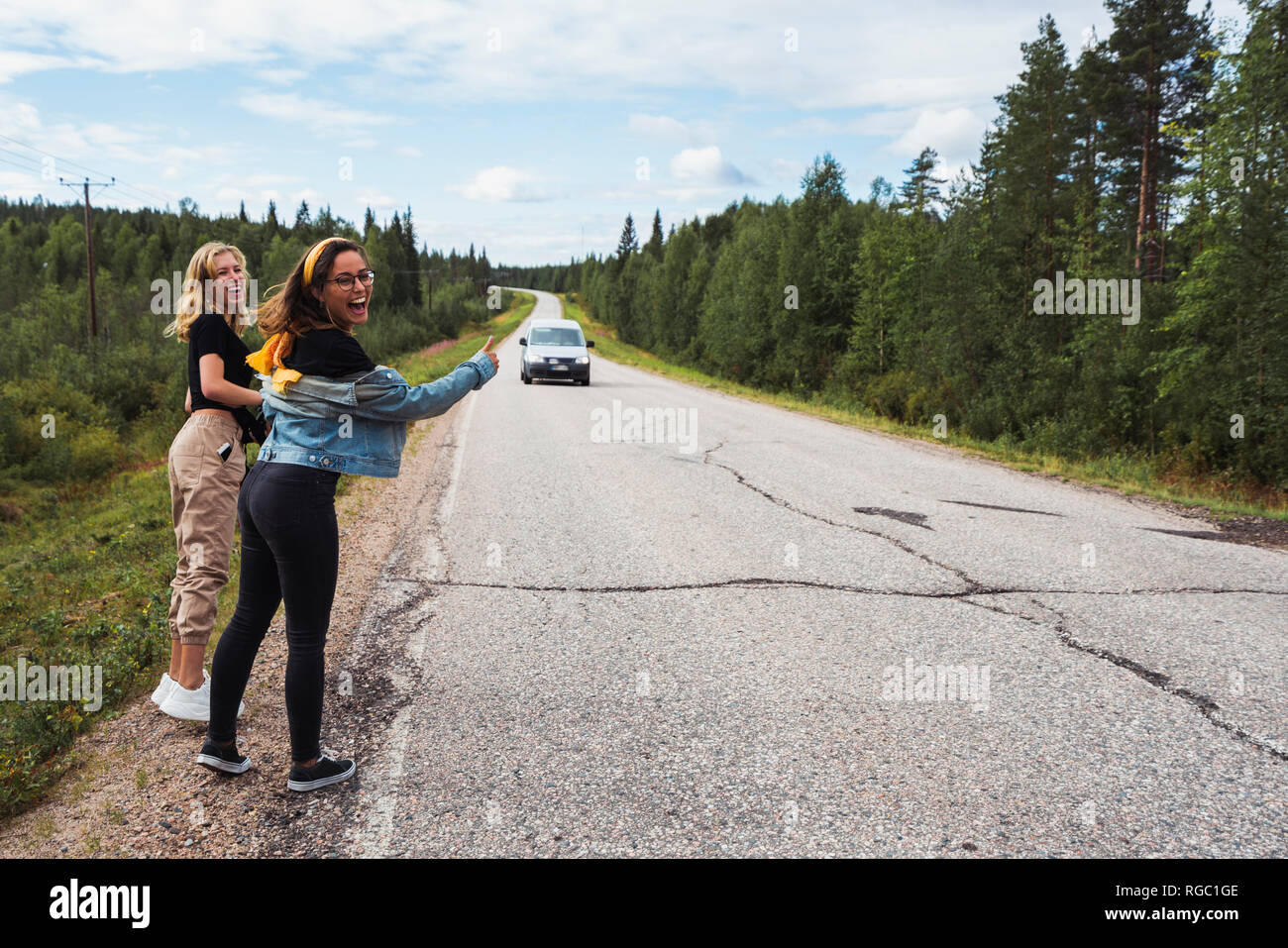 Finnland, Lappland, zwei glückliche Frauen per Anhalter auf der Straße Stockfoto