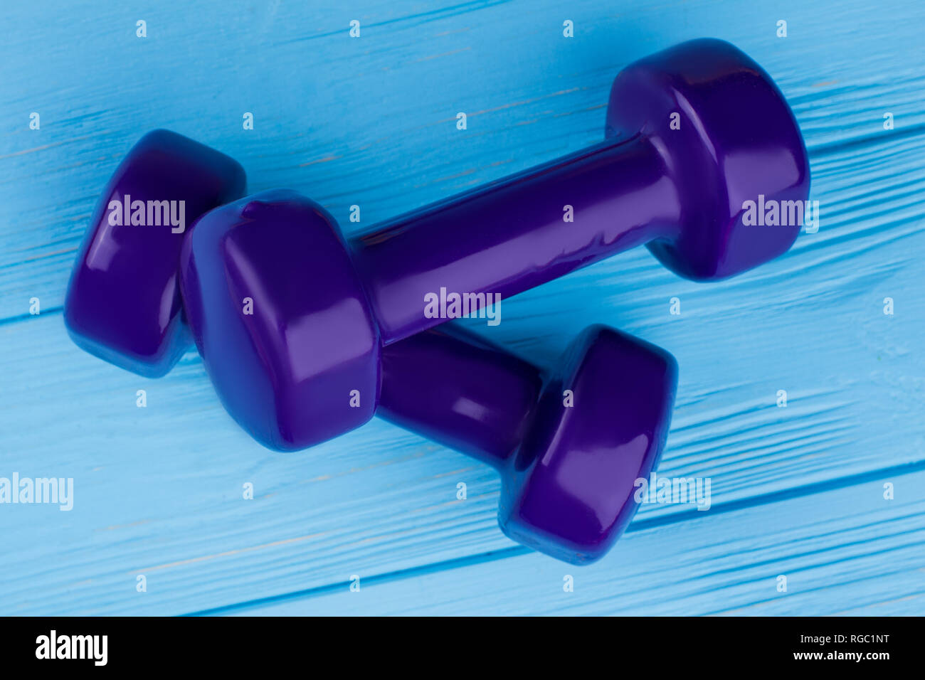 Paar Kurzhanteln auf farbigen Hintergrund. Lila hand Gewichte auf blauen Brettern. Ausrüstung für Fitness Training. Stockfoto