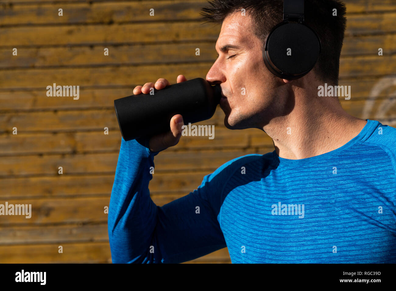 Athlet mit Kopfhörer das Trinken aus der Flasche trinken Stockfoto