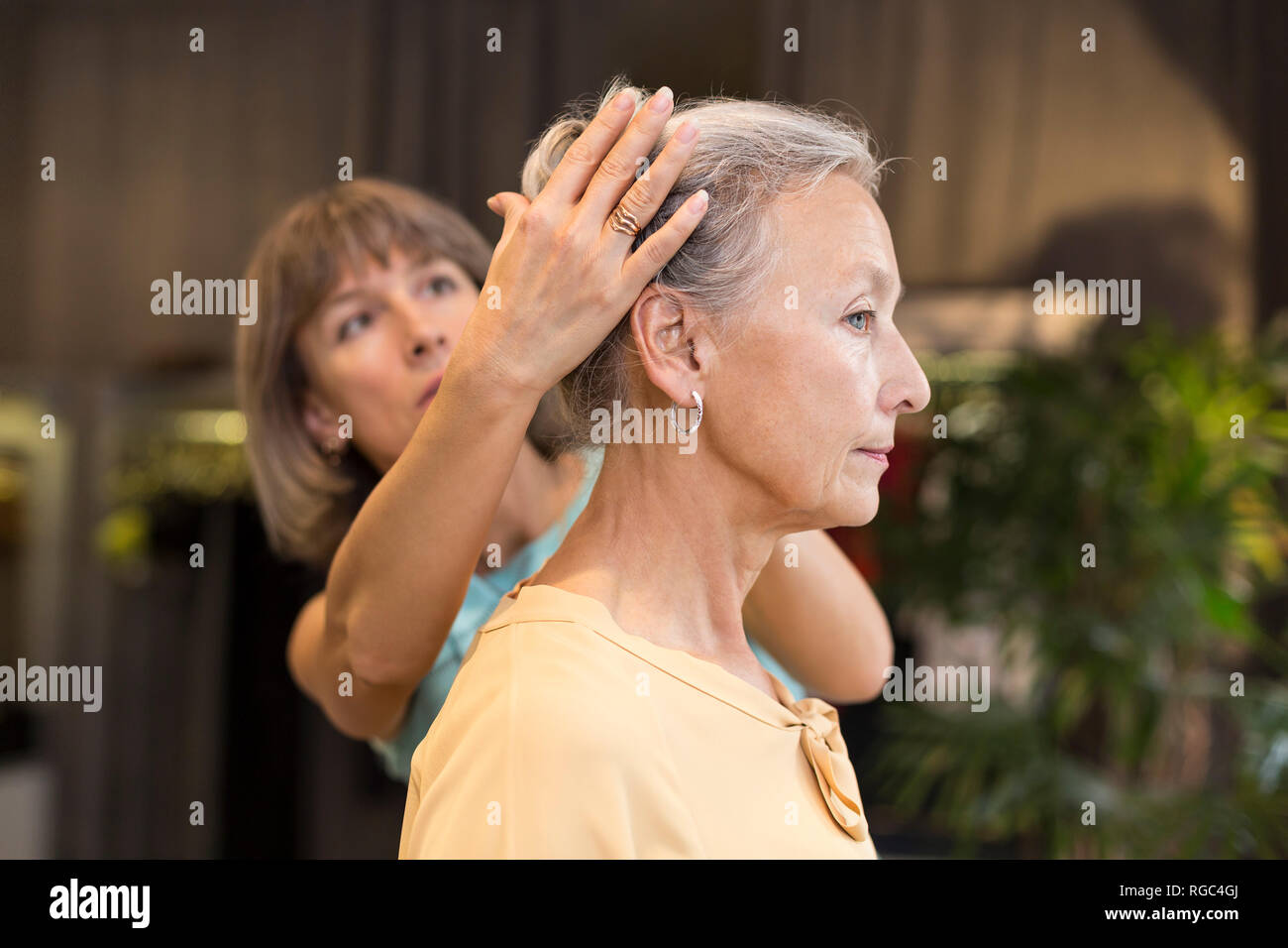 Frau helfen ältere Frau mit ihrem Haar in einem Shop Stockfoto