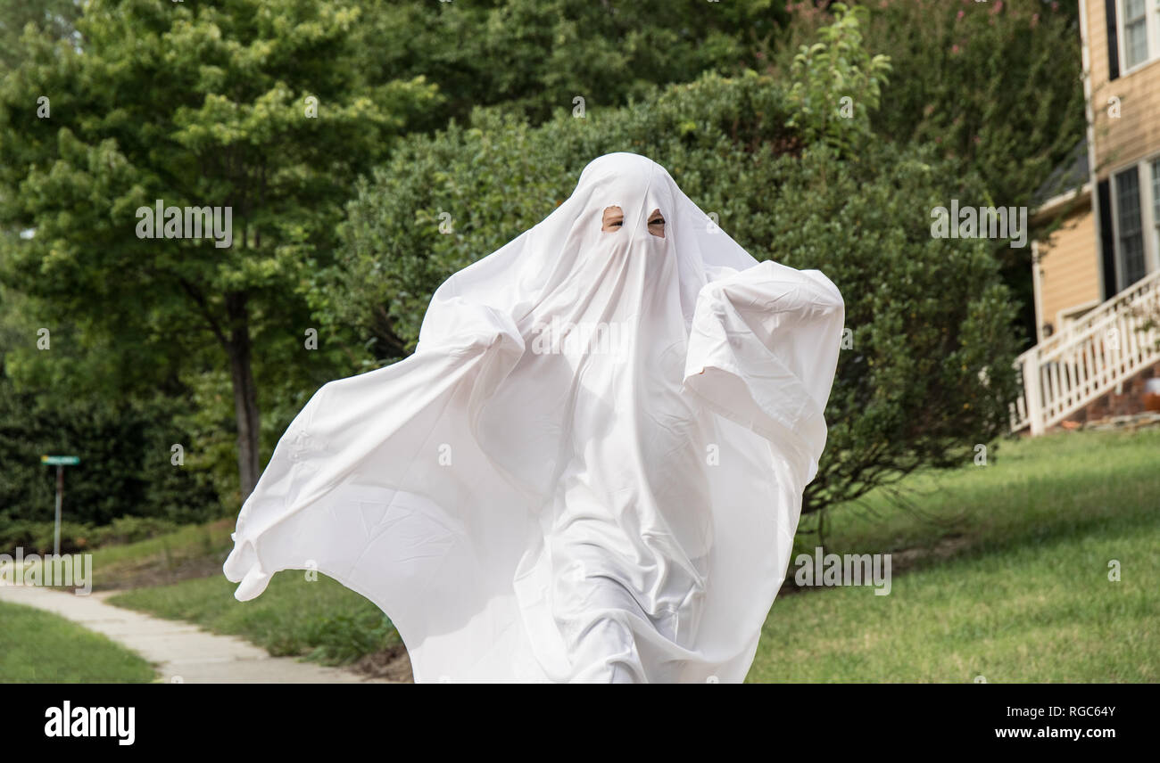 Ein Kind in einem ghost Kostüm aus einem Bettlaken auf dem Bürgersteig  Stockfotografie - Alamy