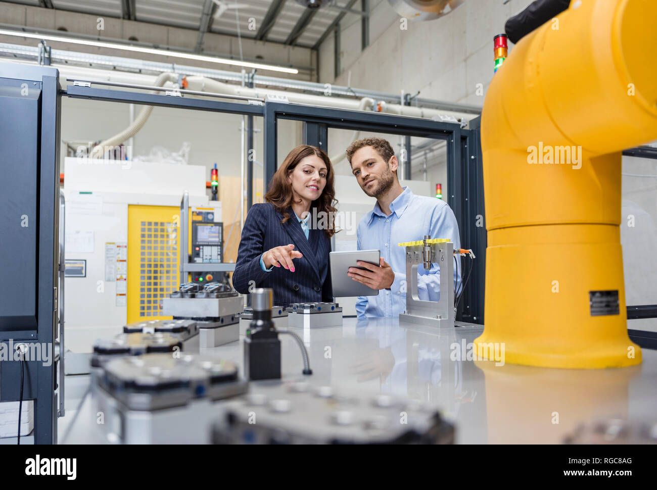 Kollegen in High-Tech Unternehmen controlling Industrieroboter, mit digitalen Tablet Stockfoto