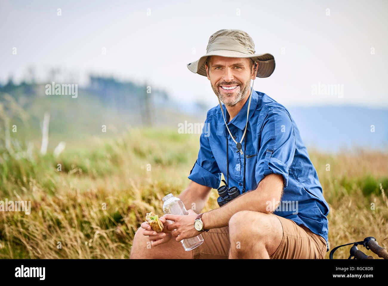 Portrait von lächelnden Mann ruhen und essen Sandwich während der Wanderung Stockfoto