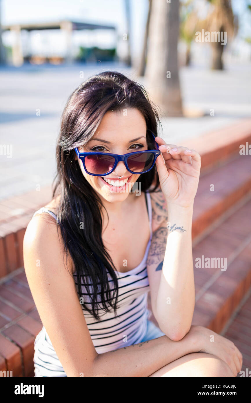 Portrait von Lachende junge Frau mit Nasen Piercing und Tattoos Stockfoto