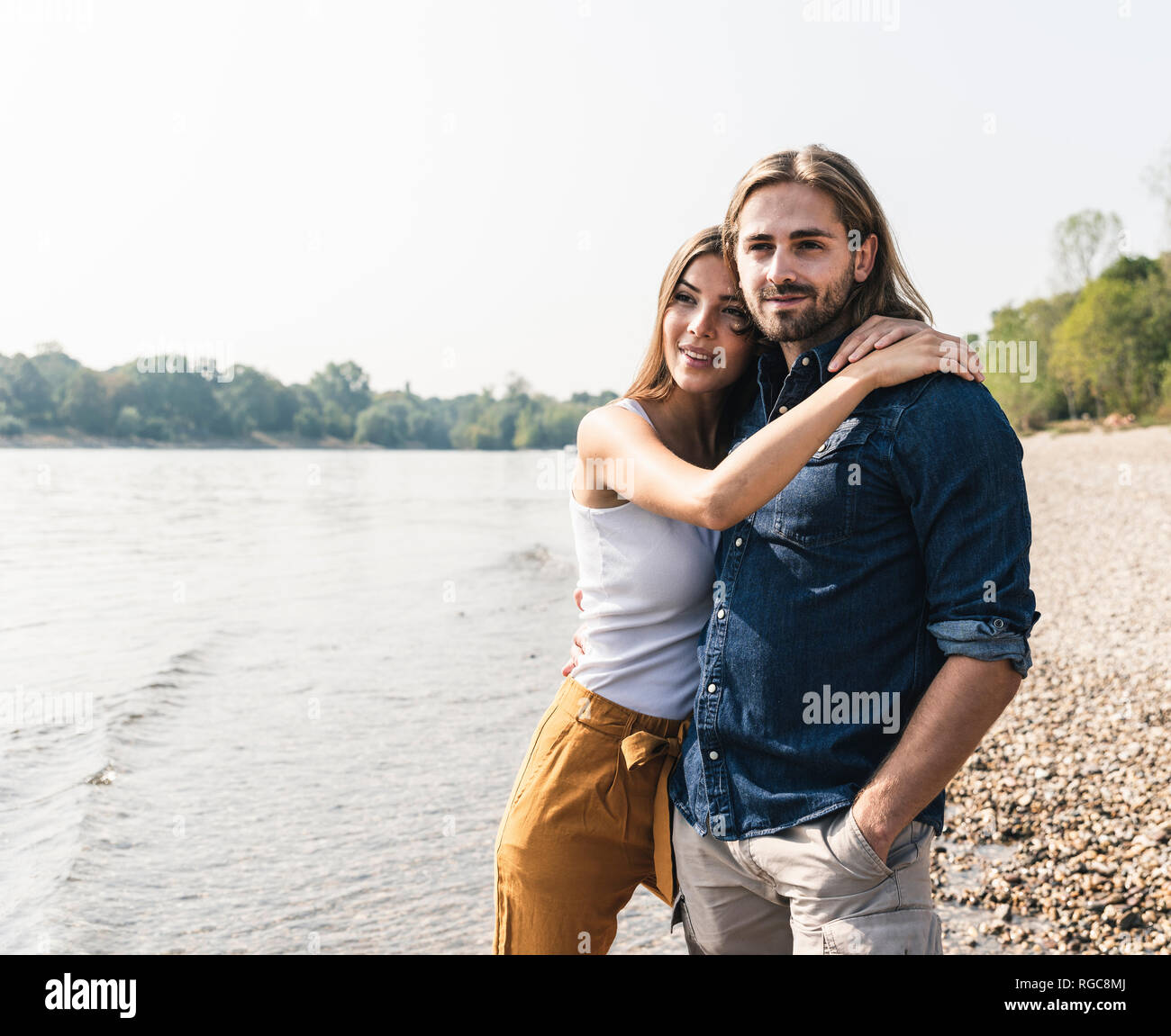 Glückliches junges Paar in Liebe umarmen am Flußufer Stockfoto