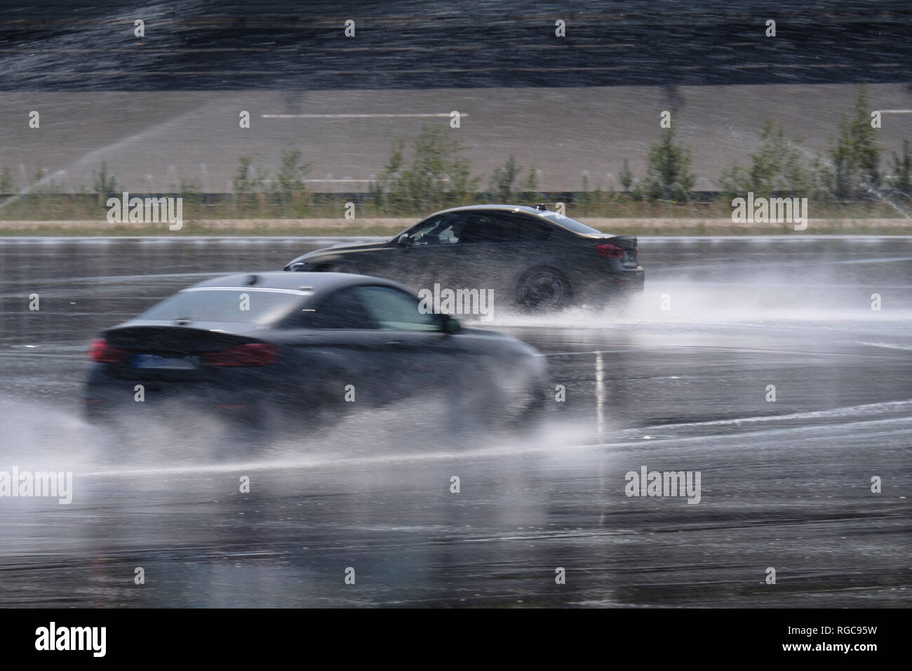 Zwei Autos fahren auf nasser Fahrbahn auf der Rennstrecke Stockfoto