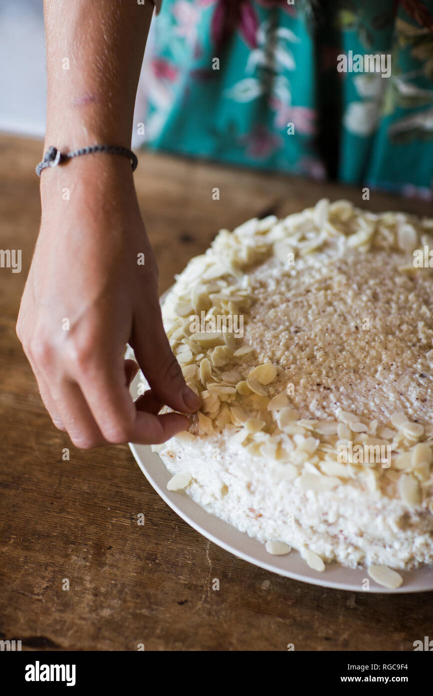 Woman's Hand home garnieren - gebackene Kuchen mit Mandelblättchen, close-up Stockfoto