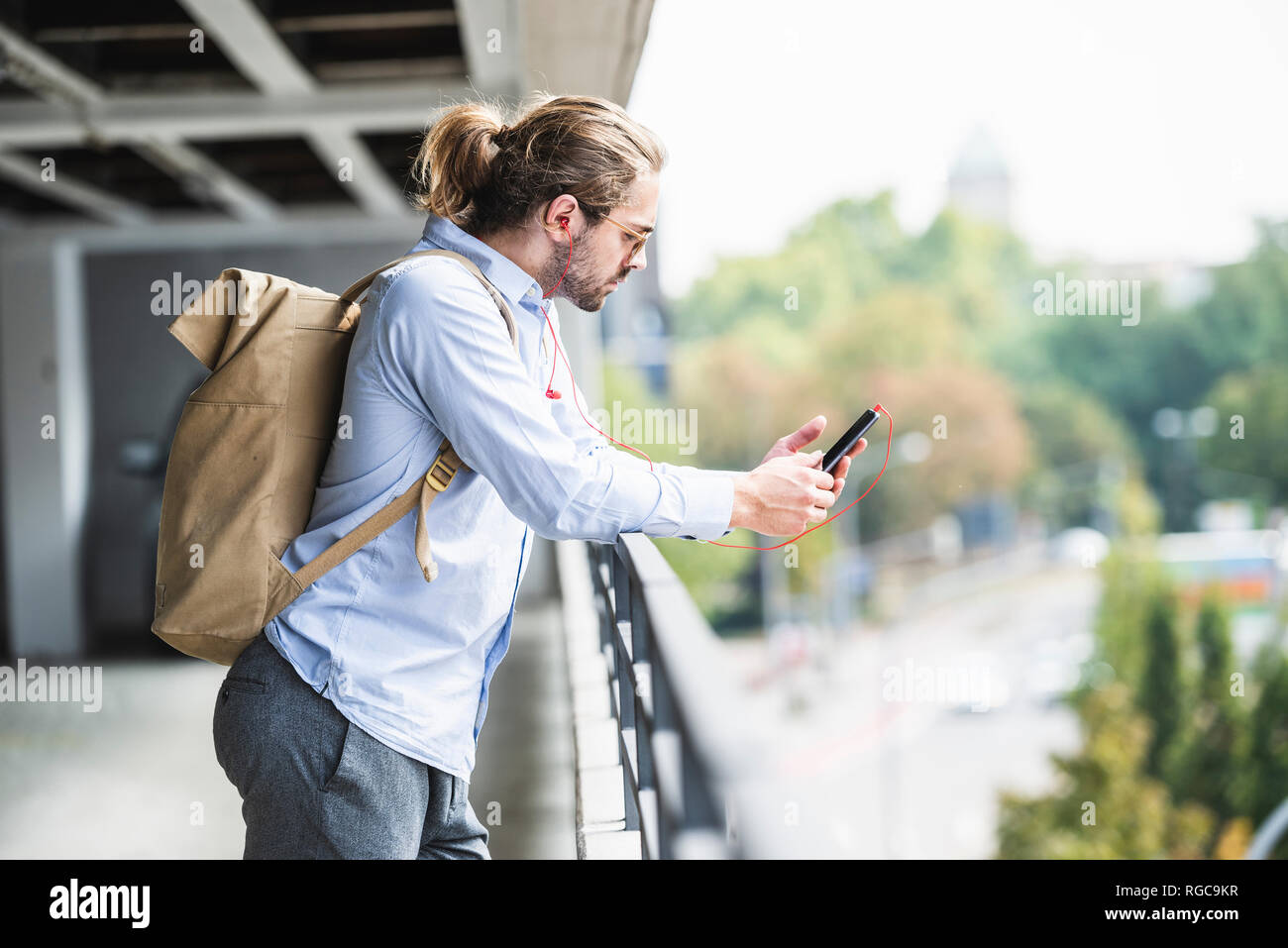 Junge Unternehmer mit Rucksack, in der Garage stehen, mit Smartphone Stockfoto