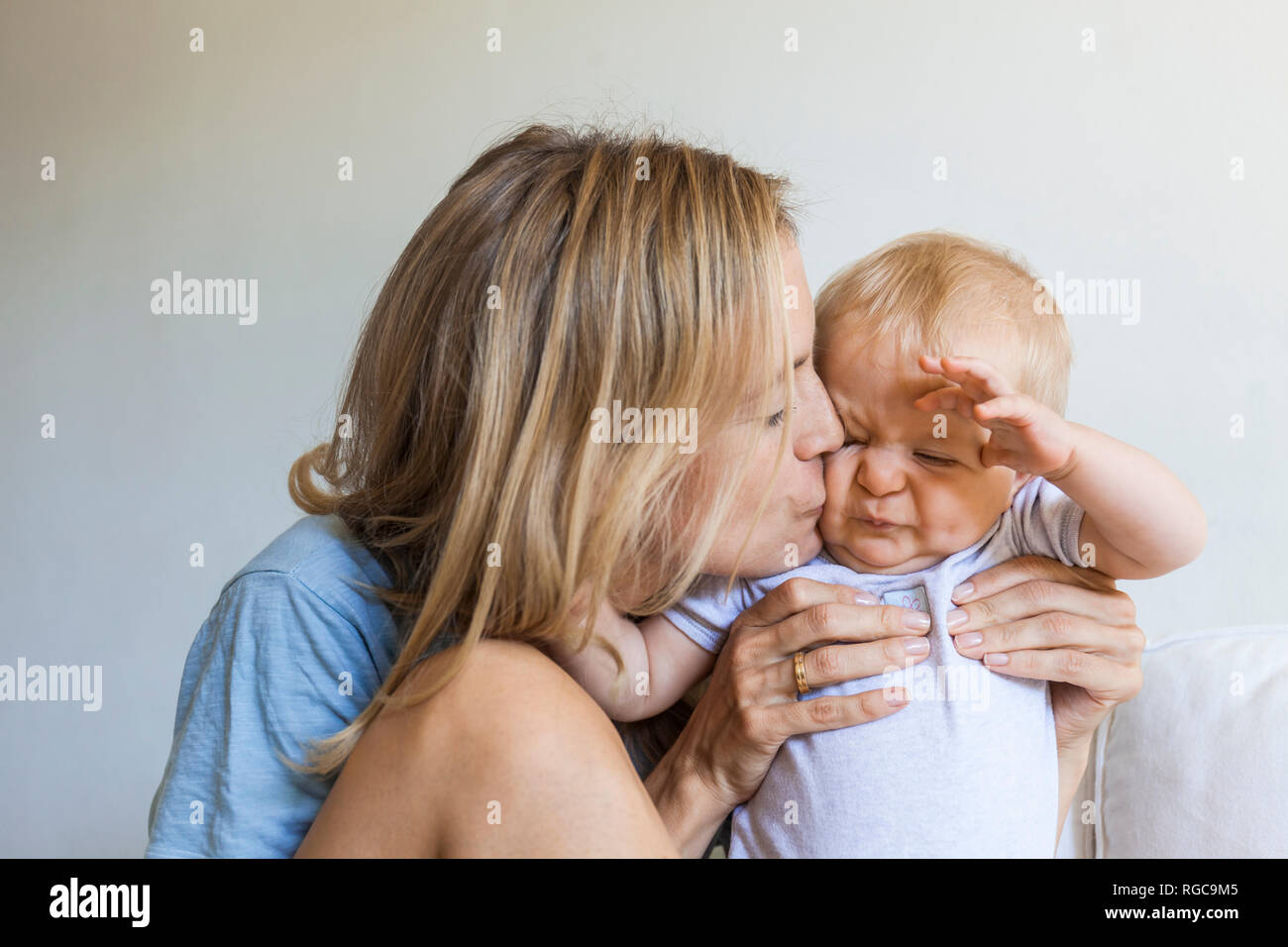 Mutter küssen ihre Grimassen baby girl Stockfoto