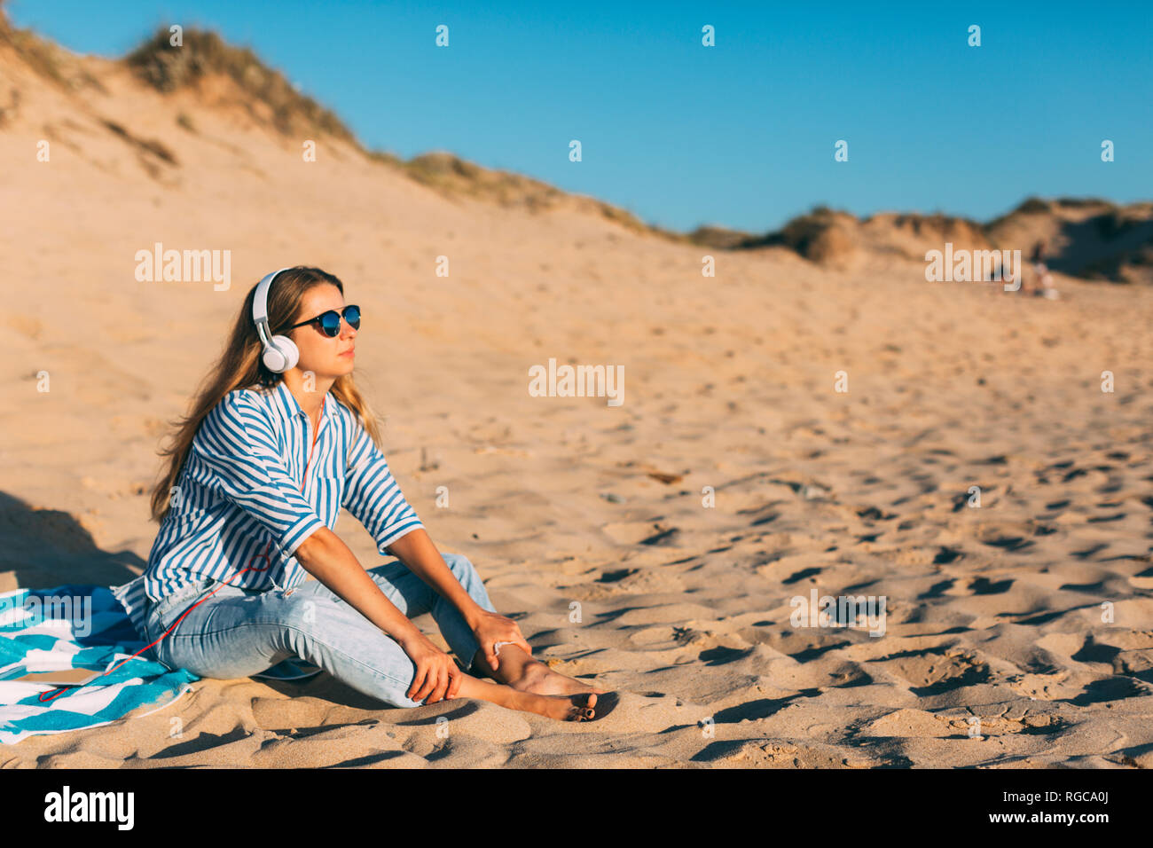 Portugal, Aveiro, Frau sitzt in der Nähe von Strand dune Musik hören mit Kopfhörern Stockfoto