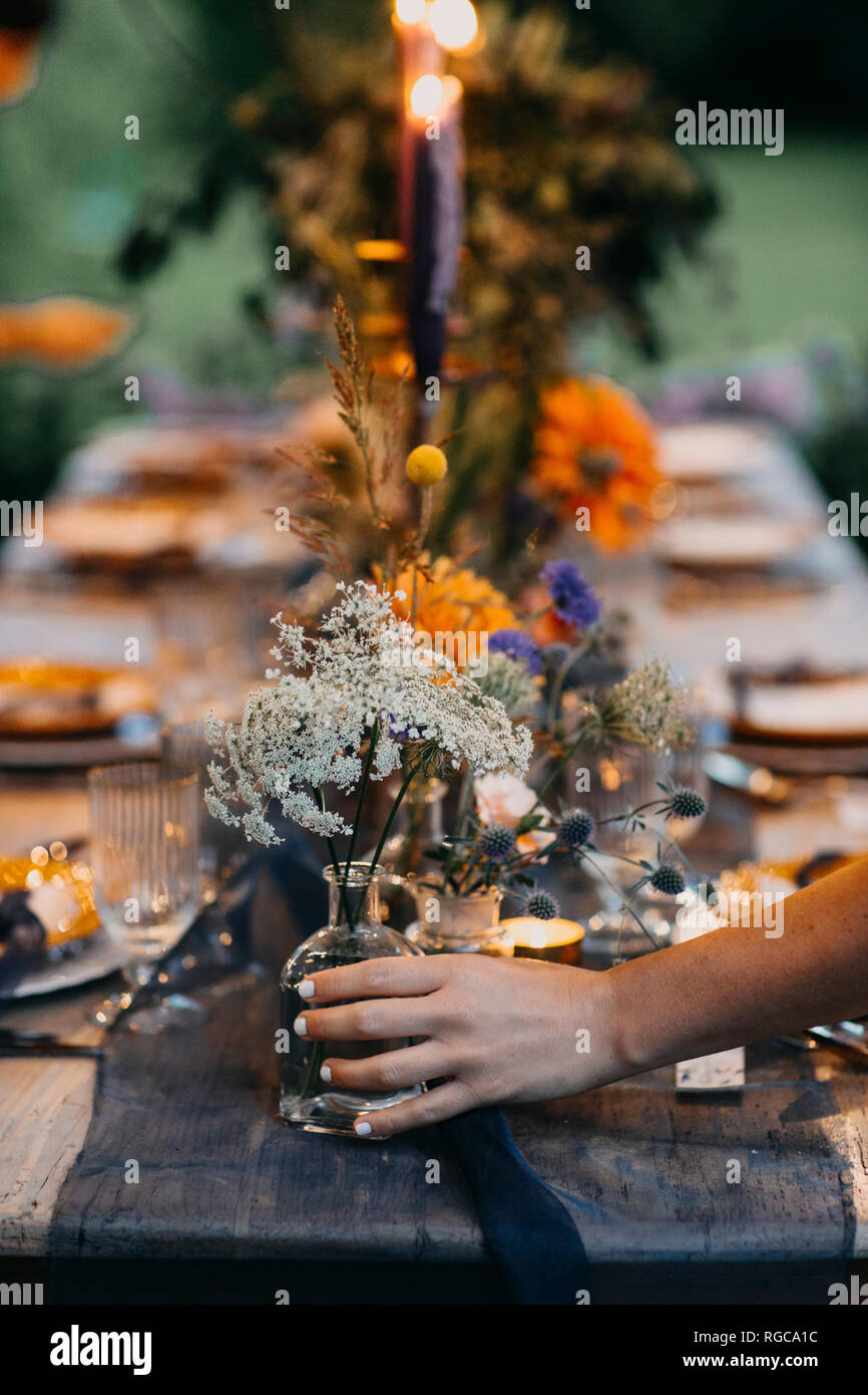 Hand Blumenvase an festlich gedeckter Tisch mit Kerzen im Freien Stockfoto