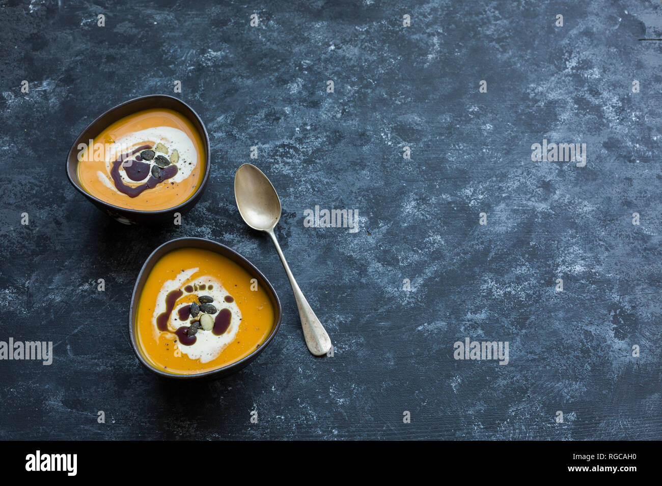 Zwei Schalen mit hausgemachten Hokkaido Kürbis Suppe, garniert mit Sahne, Kürbiskernöl und Kürbiskerne Stockfoto