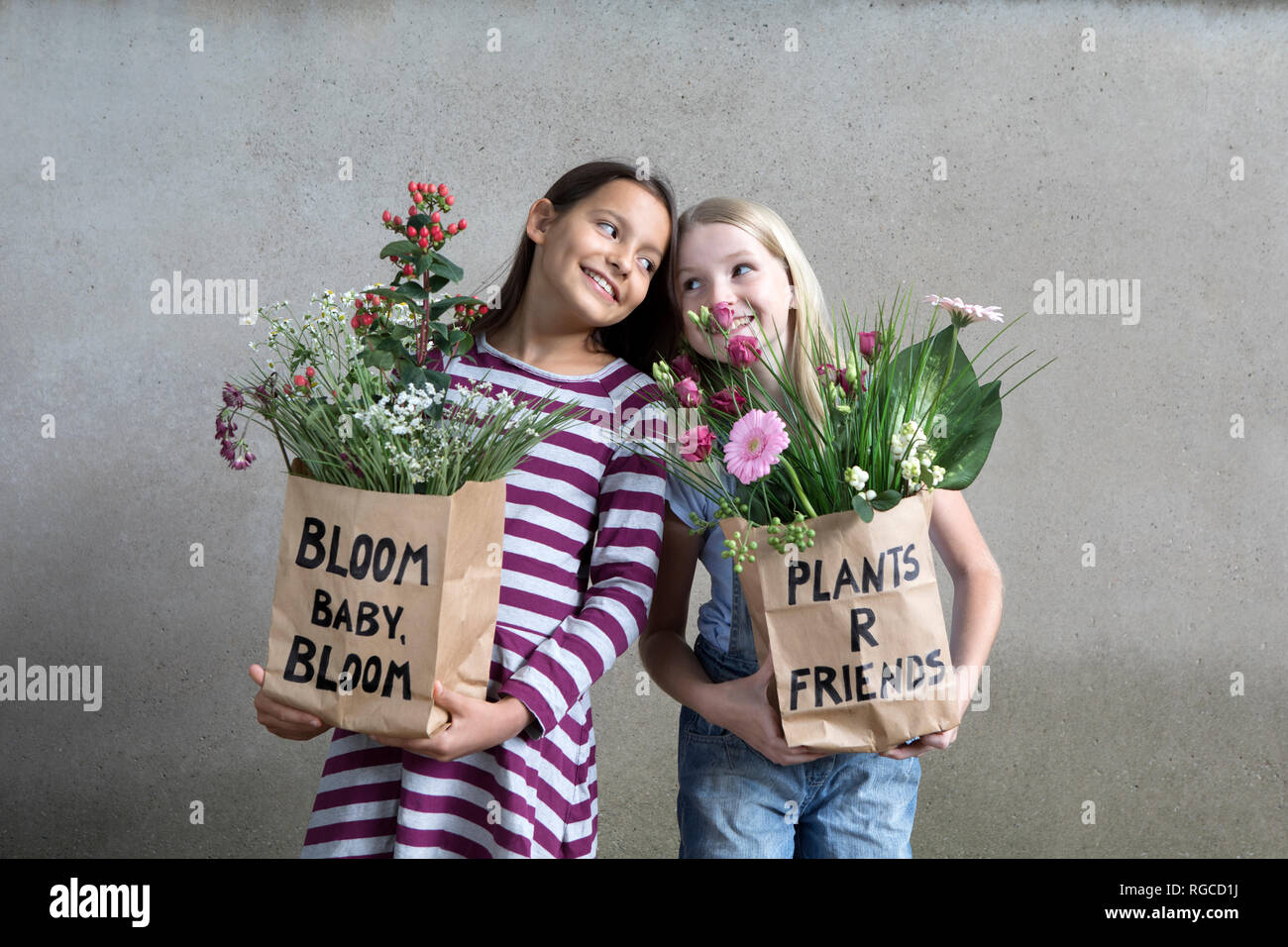 Portrait von zwei lächelnde Mädchen holding Papiertüten mit Blumen Stockfoto