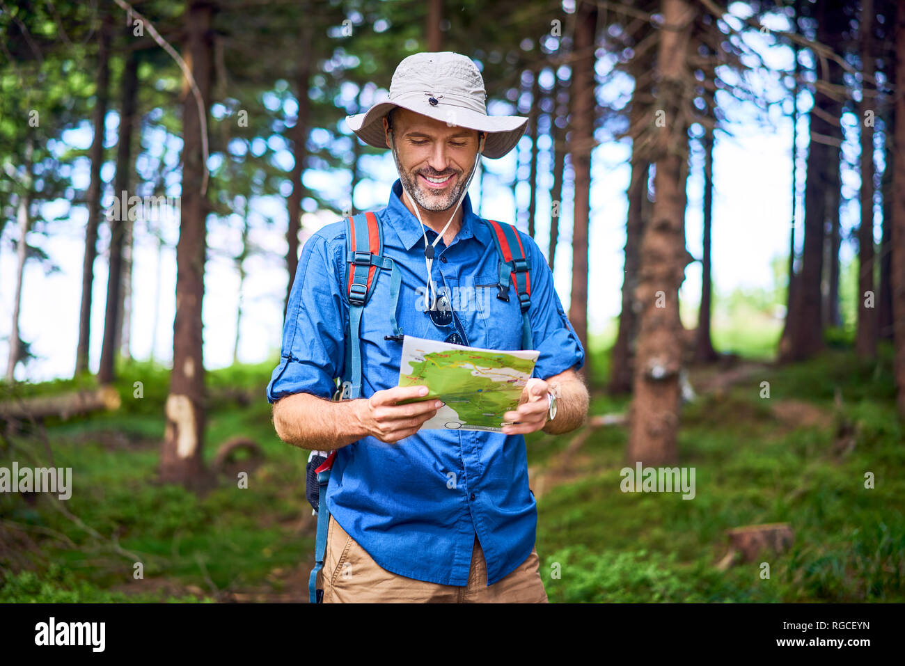 Lächelnd Mann an der Karte während einer Wanderung in den Wald auf der Suche Stockfoto