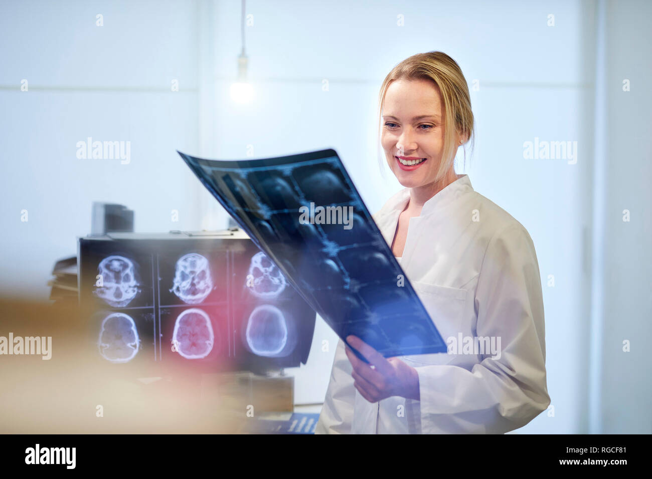 Lächelnd weibliche Arzt suchen an x-ray Image Stockfoto