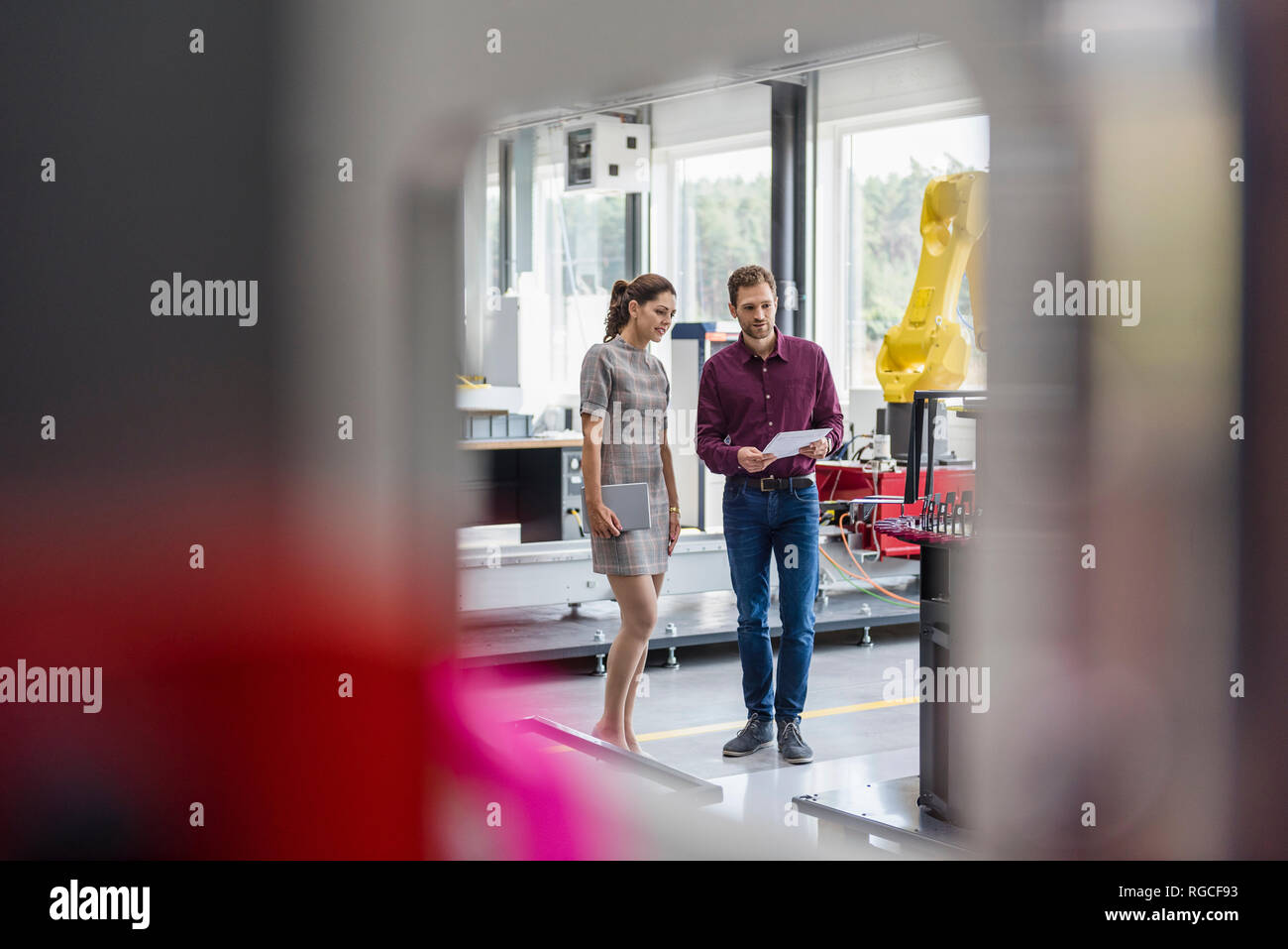 Kaufmann und Frau in einer Sitzung vor Industrieroboter in einem High-Tech-Unternehmen Stockfoto