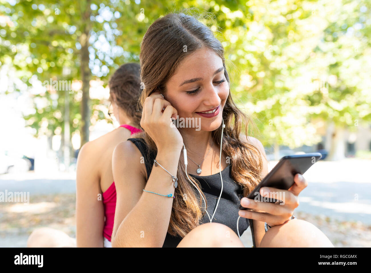 Zwei junge Frauen, die zusammen im Park Musik hören Stockfoto