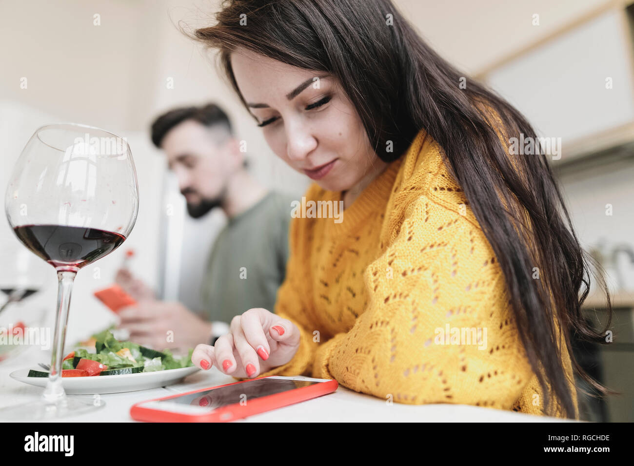 Junge Frau Kontrolle Smartphone zum Mittagessen zu Hause Stockfoto